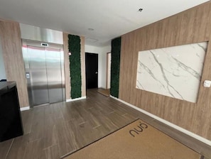 A modern hallway with a wooden floor, a marble wall, and a green wall panel. - Usaquen Loft (Bogotá)