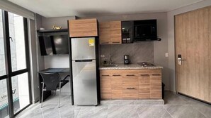 Una cocina moderna con refrigerador integrado, armarios de madera, microondas y cafetera.