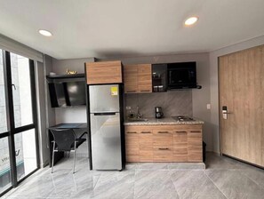 A modern kitchen with a built-in refrigerator, wooden cabinets, a microwave, and a coffee maker. - Usaquen Loft (Bogotá)