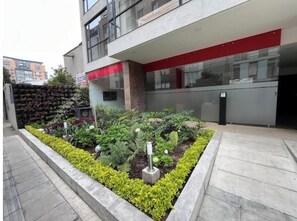 A modern building with a landscaped garden area featuring various plants and a pathway. - Usaquen Loft (Bogotá)