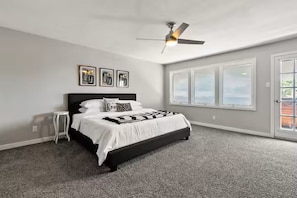 Ein Schlafzimmer mit einem Bett, einem Deckenventilator, einem Fenster und einer Tür.