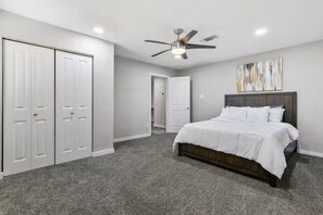 A bedroom with a bed, a ceiling fan, a wardrobe, and a door leading to another room. - World Cup • 5BR Luxury Sleeps 10 • By AT&T Stadium (Grand Prairie)