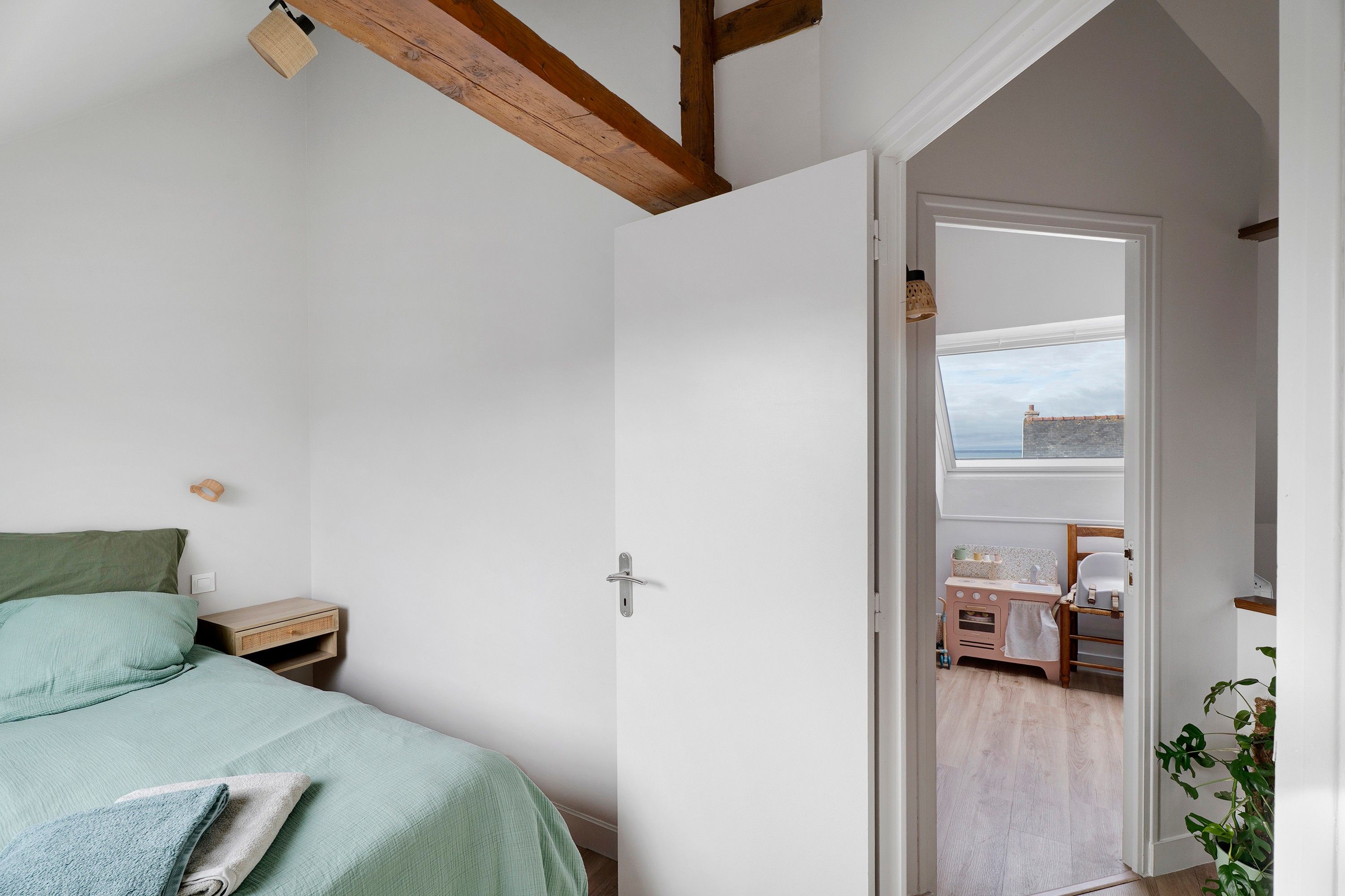 Una camera da letto con un letto, un comodino e una porta che dà su un balcone con vista sul cielo.