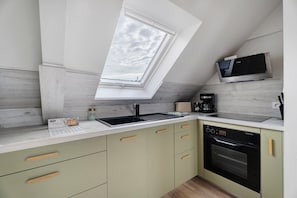 A compact kitchen with a skylight, a built-in oven, and a coffee maker.
