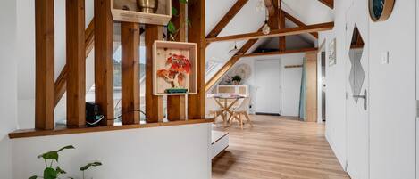 A wooden interior with a staircase, a dining area, and a kitchen visible in the background.