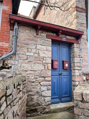 A stone building with a blue door, numbered 17, and a red mailbox.