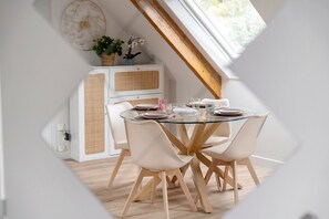 Ein Essbereich mit einem runden Glastisch, weißen Stühlen und einem weißen Schrank mit einem Gewebepaneel.