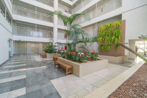 Un atrium à plusieurs niveaux, doté d’un jardin central, de bancs et d’un escalier.