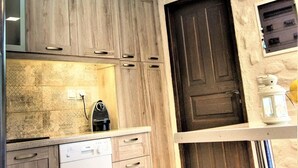 Una cocina con armarios de madera, un ventilador de techo, un lavavajillas y una puerta con un pequeño ventanal.
