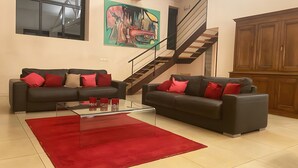 Ein Wohnzimmer mit zwei Sofas, einem Couchtisch, einem roten Teppich, einer Treppe und einem Holzschrank.