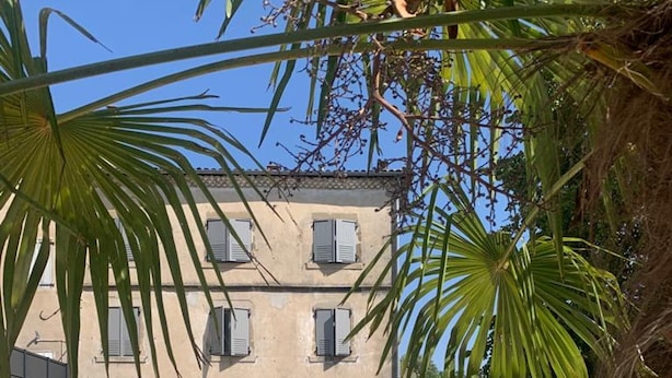 A pool with a wooden deck, a building with shutters, and palm trees. - La Maison des Remparts: Private Pool, Wi-Fi, Air Conditioning – Holiday Home in Clérieux (Clérieux)