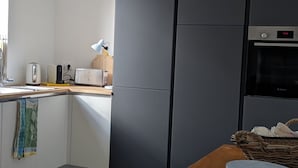 A modern kitchen with a wooden countertop, a bowl of fruit, a toaster, and a Bosch oven. - La Maison des Remparts: Private Pool, Wi-Fi, Air Conditioning – Holiday Home in Clérieux (Clérieux)