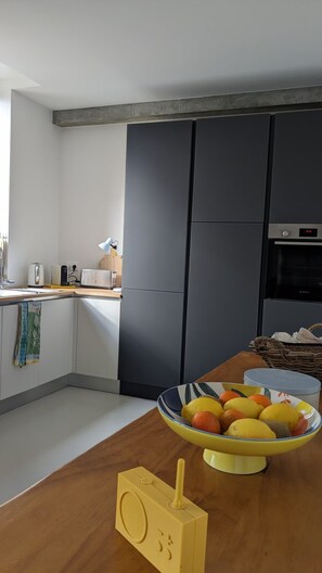 Une cuisine moderne avec un plan de travail en bois, un saladier de fruits, un grille-pain et un four Bosch.
