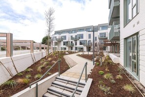 A modern apartment building with a central courtyard, outdoor seating area, and a staircase leading to the entrance. - Apex Executive Apartments - The Lookout (Dublin)