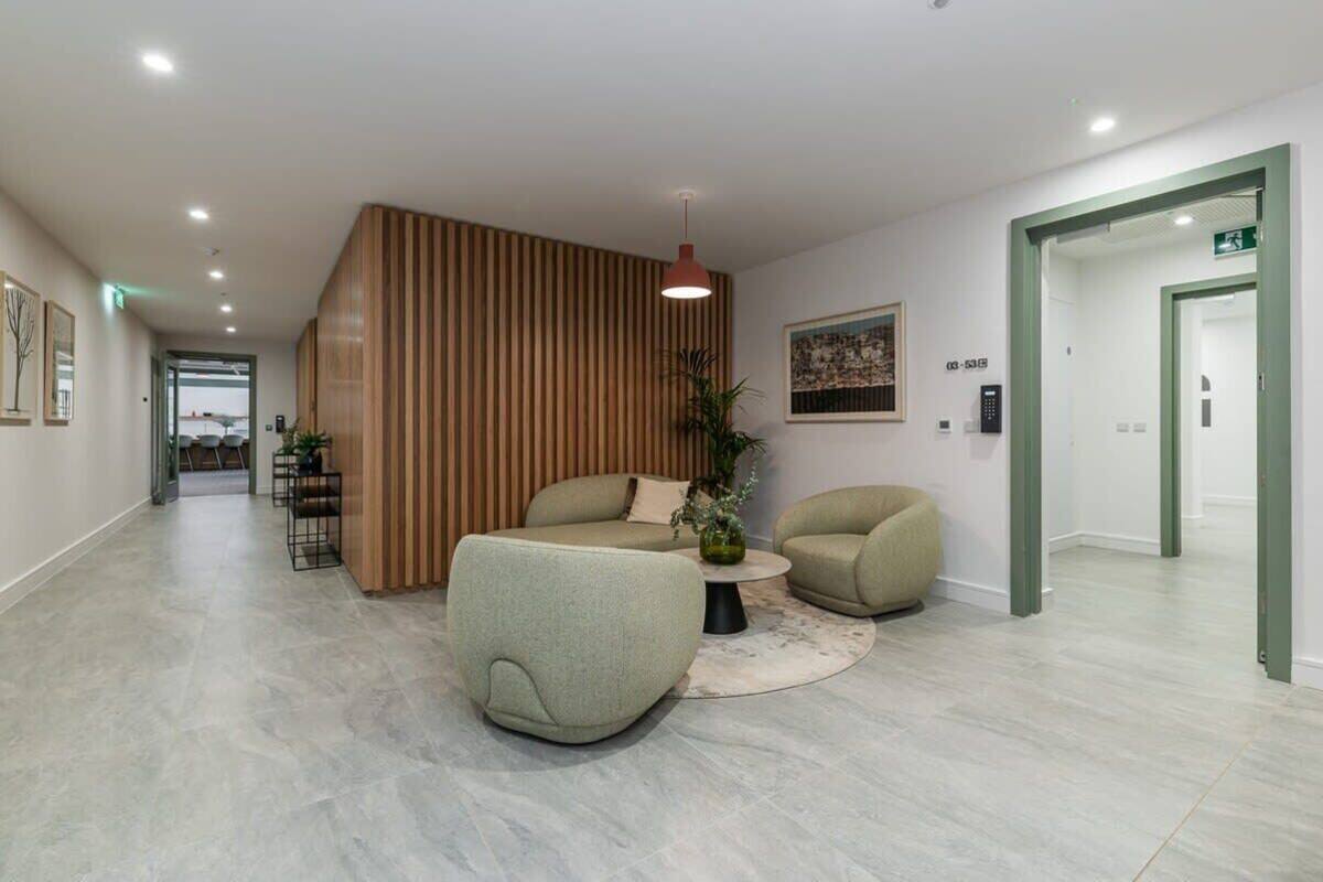A modern lobby with a reception desk, seating area, and a staircase.