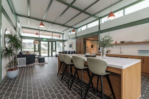 Una cucina moderna con isola centrale, sgabelli da bar e un'area salotto con divano e poltrone.