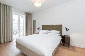 Una camera da letto con un letto, comodini, una lampada e vista dalla finestra.
