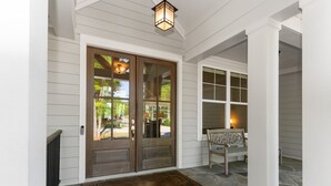 A house entrance with a stone-paved porch, a bench, and a double door with glass panels. - Ultimate Vacation| Dock| Fire Pit|Kayaks|Game Room (Eatonton)
