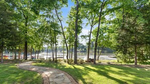 A stone pathway leading to a lake with trees and a dock. - Ultimate Vacation| Dock| Fire Pit|Kayaks|Game Room (Eatonton)