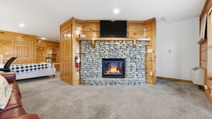 Una habitación con chimenea de piedra, cama con colcha a cuadros y paneles de madera.