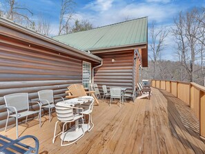 A log cabin with a deck, outdoor seating, and a view of the surrounding trees. - A Family Affair #712 (Gatlinburg)