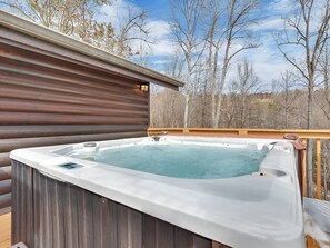 A hot tub on a wooden deck with a view of trees and a building in the background. - A Family Affair #712 (Gatlinburg)