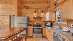 A wooden cabin-style kitchen with a refrigerator, stove, oven, microwave, and sink. - A Family Affair #712 (Gatlinburg)