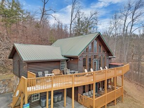 A log cabin with a deck, outdoor seating, and a stone wall. - A Family Affair #712 (Gatlinburg)