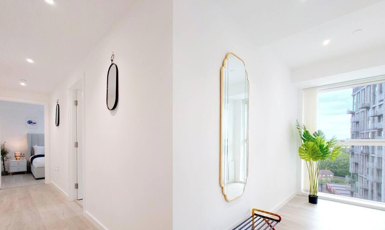 A modern interior with a large mirror, a potted plant, and a view of buildings outside.
