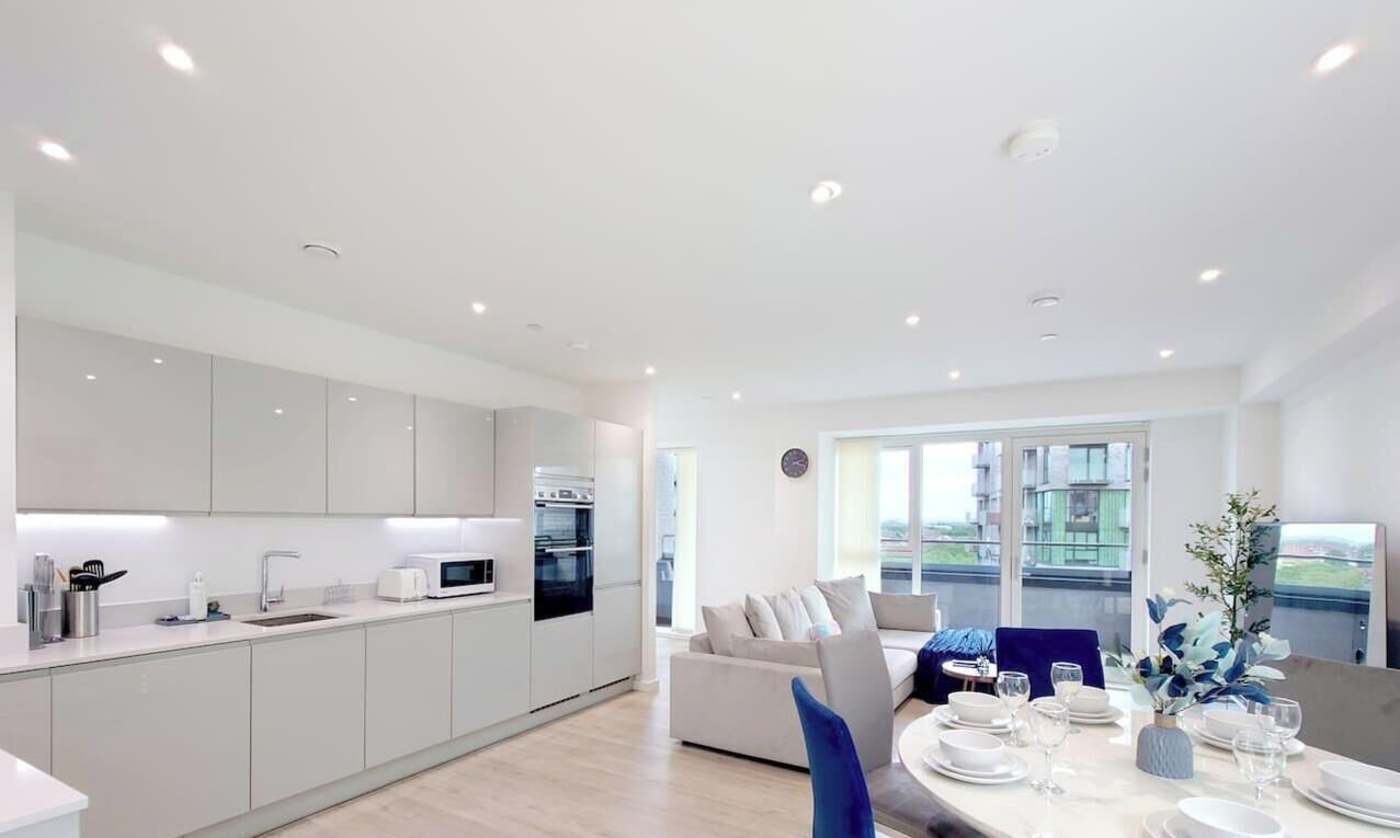 Een moderne keuken met inbouwapparatuur, een eethoek met een tafel voor vier personen, en een groot raam met uitzicht op de stad.