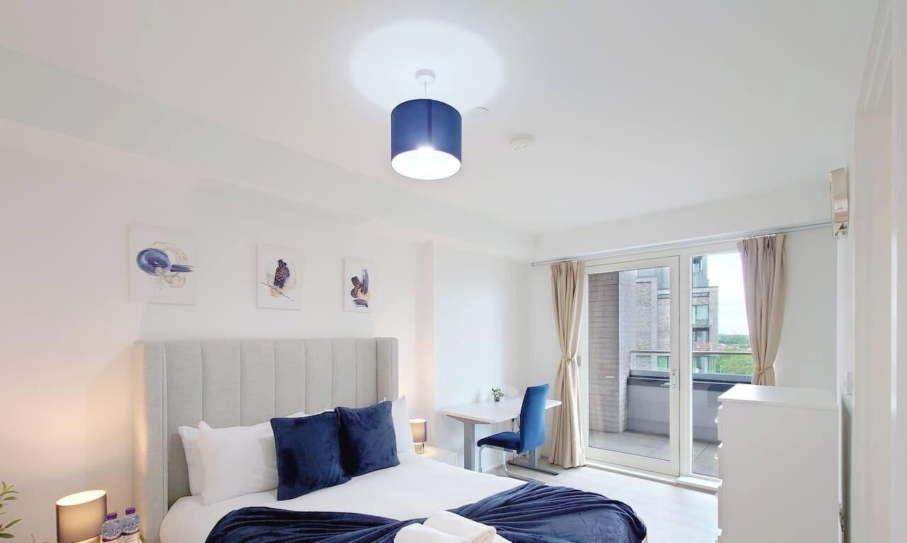 Una habitación de hotel con cama, escritorio, silla y balcón con cortinas.