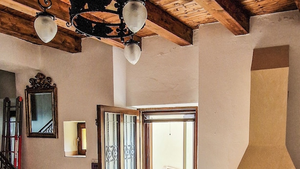 Un interior amplio con techo de madera, chimenea y escalera que lleva a un espacio abierto.