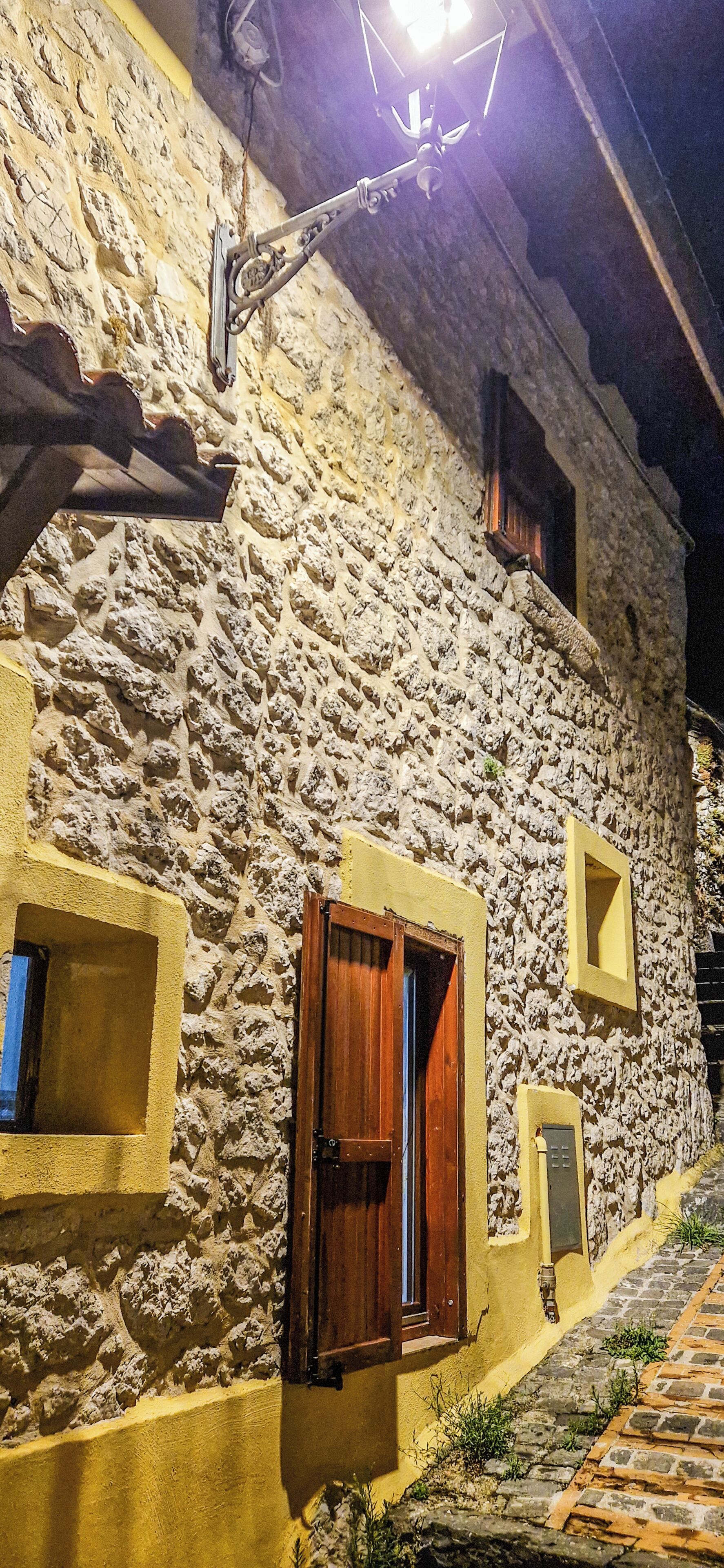 Un edificio in pietra con facciata gialla, una porta di legno e una piccola finestra.