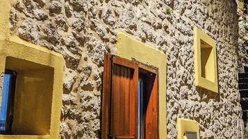 Un edificio in pietra con facciata gialla, una porta di legno e una piccola finestra.