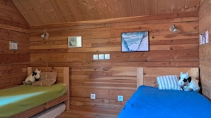 Una cabina con due letti di legno, un poster incorniciato e un quadro appeso al muro.