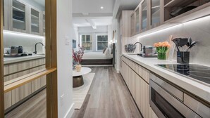 A modern kitchen with a central island, built-in appliances, and a view to the living area. - 17John: Signature King Studio Apartment (New York)