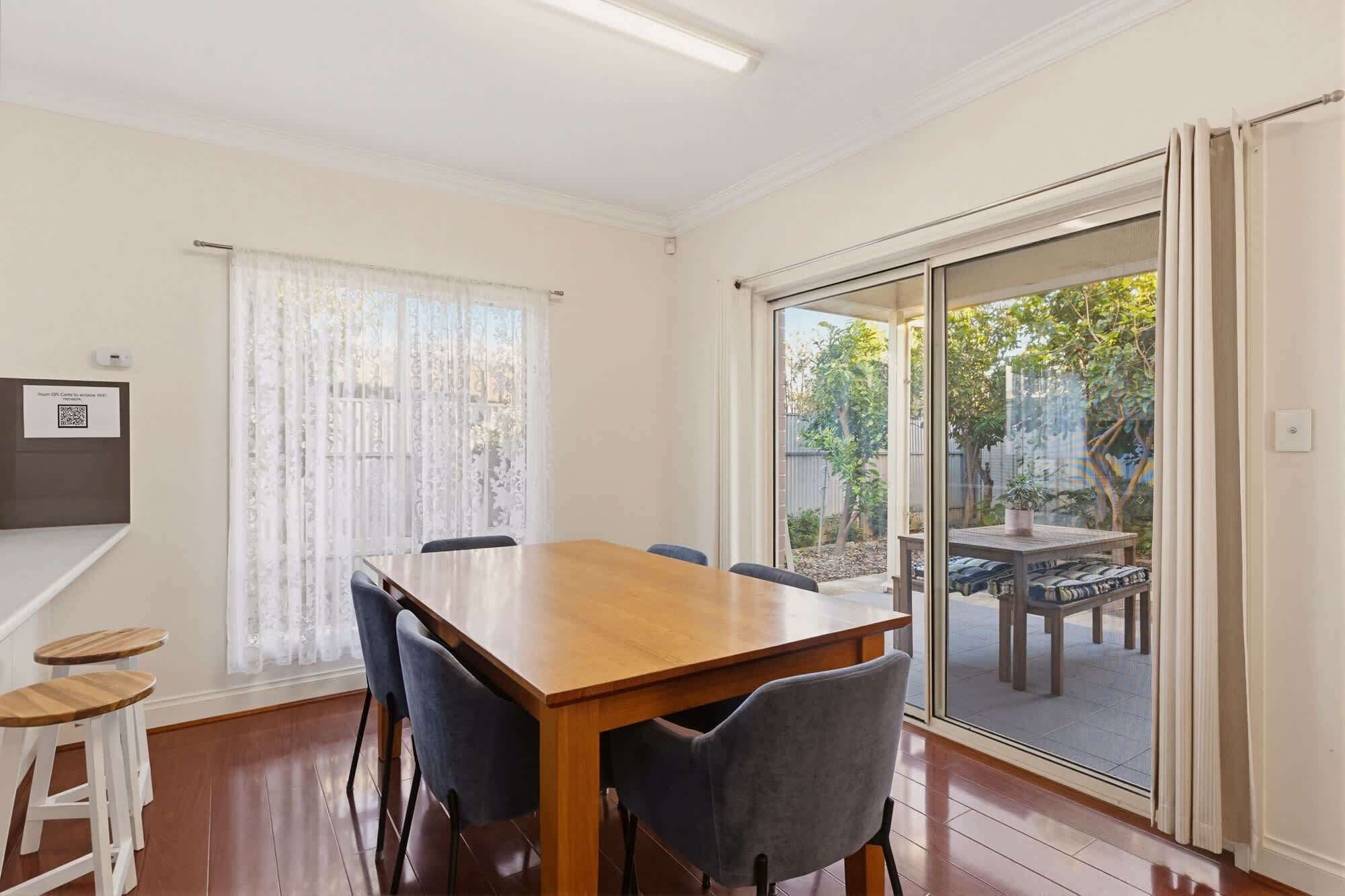 A dining area with a wooden table, chairs, and a view through a sliding glass door to an outdoor patio.