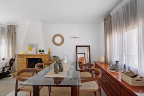 A dining area with a glass table, wooden chairs, a fireplace, and a mirror on the wall.