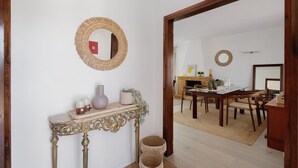 A dining area with a wooden table and chairs, a console table with decorative items, and a mirror on the wall.