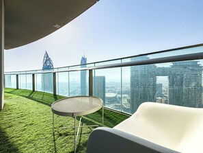 A modern rooftop terrace with a glass railing, a round table, and a white lounge chair. - Burj Vista 2 Bedroom Apartment with Burj View 5407 (Dubai)