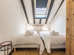 Ein kleiner, gemütlicher Raum mit zwei Betten, einem Oberlicht und Holzboden.