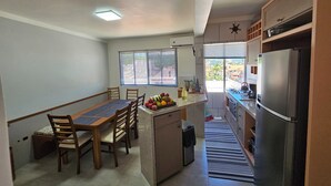 A compact kitchen with a dining area, a refrigerator, and a window with blinds. - Penthouse with terrace (Florianópolis)