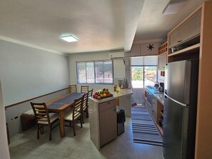 A compact kitchen with a dining area, a refrigerator, and a window with blinds. - Penthouse with terrace (Florianópolis)