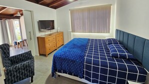 A bedroom with a bed, a TV, a wooden dresser, and a window with blinds. - Penthouse with terrace (Florianópolis)
