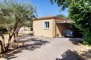 A single-story building with a garage, surrounded by trees and a gravel driveway.