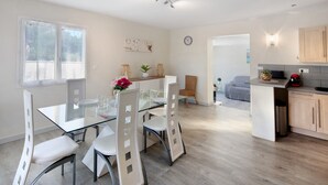 Une cuisine moderne avec un coin repas, des meubles en bois et une table en verre.