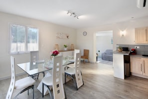 A modern kitchen with a dining area, wooden cabinets, and a glass table.