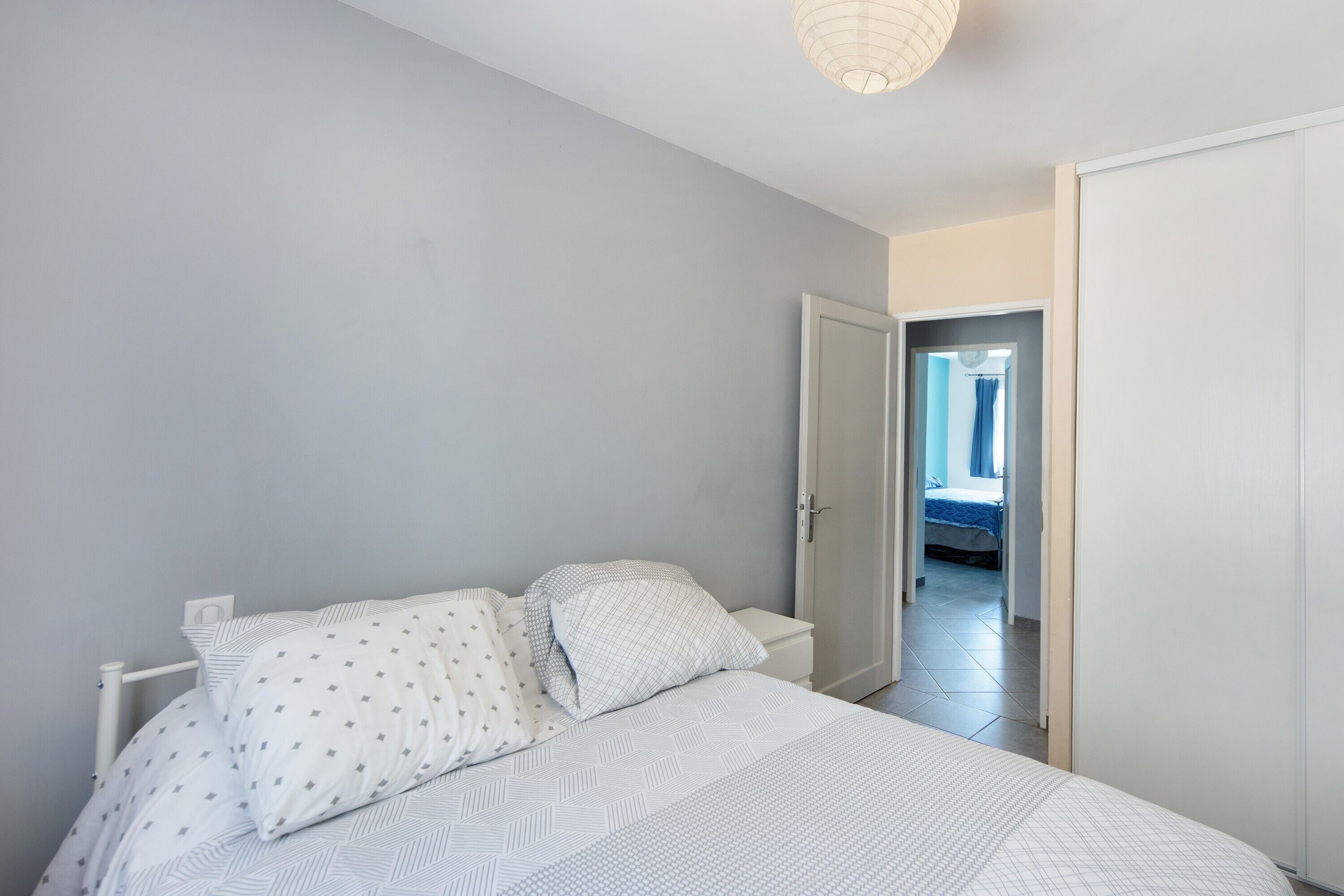 Un dormitorio con cama, mesita de noche y una puerta que da a otra habitación.