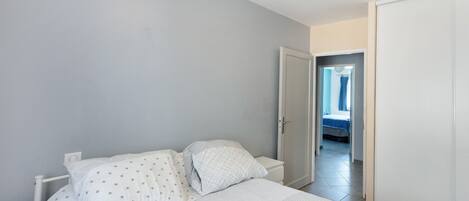 Un dormitorio con cama, mesita de noche y una puerta que da a otra habitación.