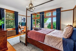 Ein Schlafzimmer mit Himmelbett, Schreibtisch und Blick ins Grüne.
